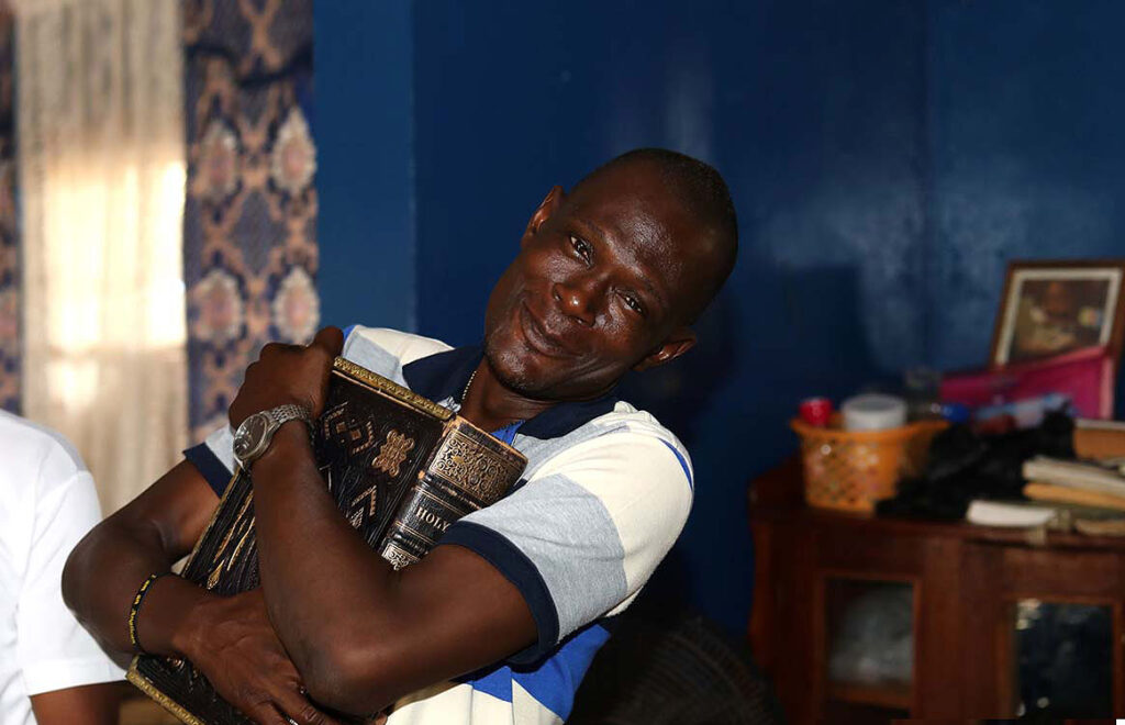Teacher at Bo School, Sierra Leone holding bible 